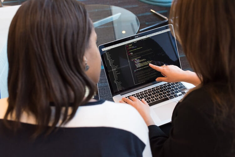 두명의 여자가 컴퓨터 화면에 HTML 코드를 보고 수정하고 있다
